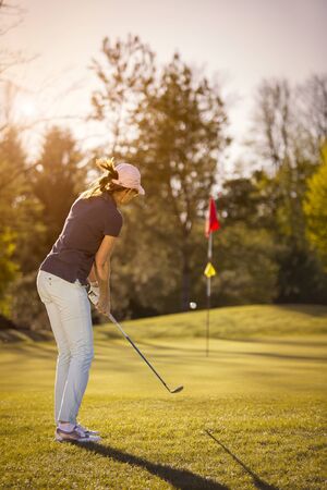 Female golf player pitching towards flag.の写真素材