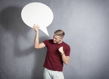 Frustrated man holding white blank speech bubble.の写真素材