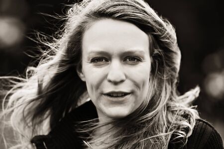 Close-up portrait of young happy woman outdoors, sepia toned.の写真素材