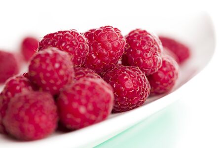 Close up of fresh delicious raspberry on elegant plate, isolated on white background.の写真素材