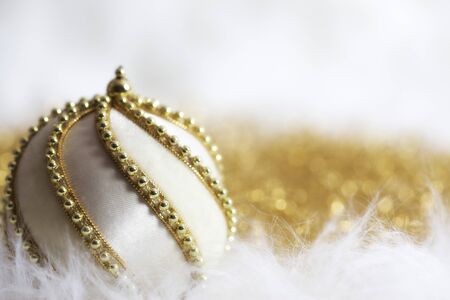 White Christmas bauble adorned with golden chain on twinkling golden/white backgroundの写真素材