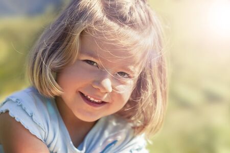 Portait of innocently smiling girl sitting in grass, close up.の写真素材