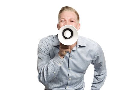Great news: Young joyful businessman shouting with megaphone isolated on white background.の写真素材