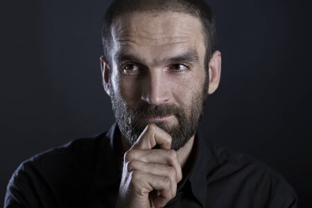 Portrait of serious man looking thoughtful, isolated on black background.の写真素材