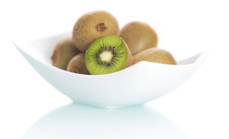 Fresh whole kiwi and slice on elegant plate isolated on white background.の写真素材