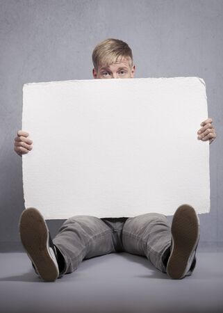 Upset man holding white empty panel.の写真素材