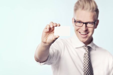 Cheerful businessman presenting white empty card.の写真素材