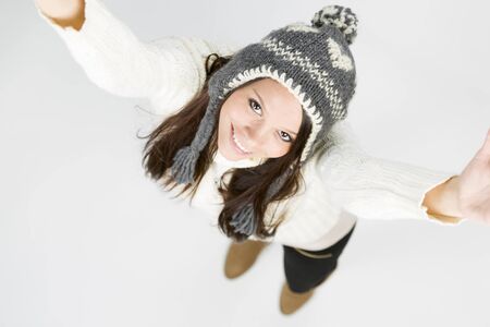 Adorable girl in winter clothes looking up with raised arms.の写真素材
