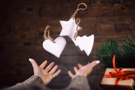 Woman hands throws up homemade Christmas tree toys. dark background.