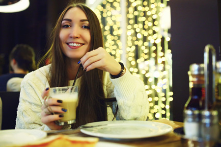 Beautiful young woman drinking coffee at cafe. Tonned. Selective focus.の写真素材