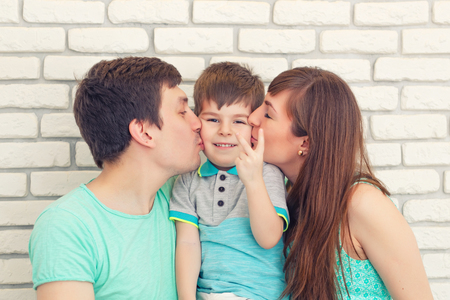 Happy and smiling young family Portrait on Brick wall Background. Father and Mother with Little Baby boy. Parents with Childの写真素材
