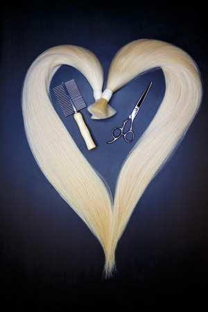 hair extension equipment of natural blonde hair. heart shape on a dark background.の写真素材