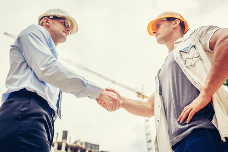 Architect engineer shaking hands other hand at construction site.  Business teamwork, cooperation, success collaboration conceptの写真素材