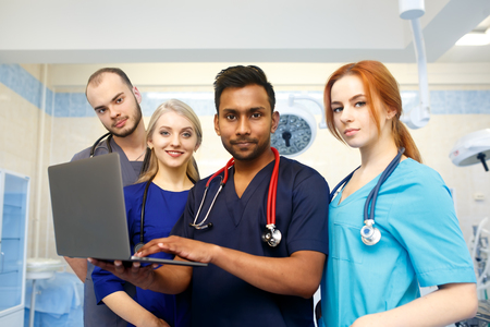 Multiracial team of young doctors working on laptop computer in medical office.の写真素材