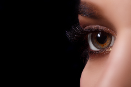 Eyelash Extension Procedure. Woman Eye with Long Eyelashes after Extension Procedure. White eyelashes. Dark background. Makeup. Close up, selective focus.の写真素材