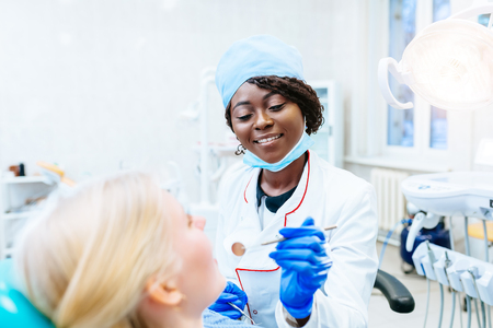 African american female dentist treating patient at clinic. Dental clinic concept.の写真素材