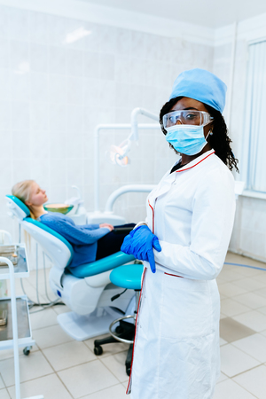 Young smiling African american female dentist in front of patient at clinic. Dental clinic concept.の写真素材