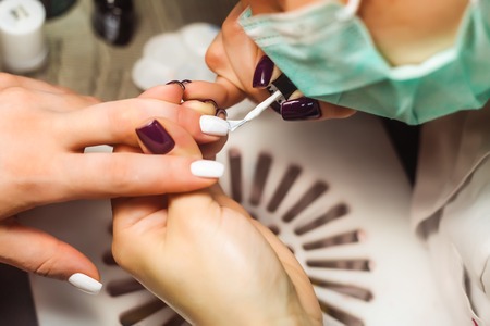 Woman hands in a nail salon receiving a manicure. Close up, selective focus. Top view.の写真素材