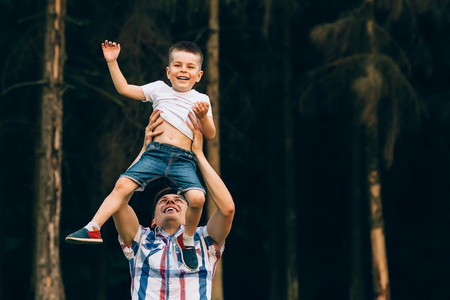 Father throwing his little son up in the air. Family time together. Happy little boy having fun with his dad outdoorsの写真素材