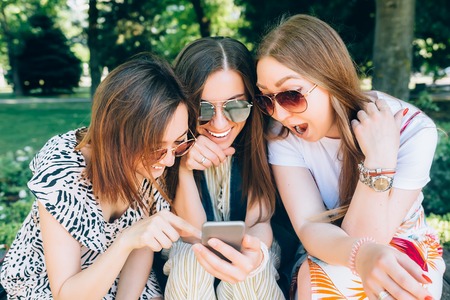 Happy friends in the park on a sunny day . Summer lifestyle portrait of three multiracial women...