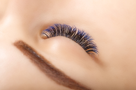 Eyelash Extension Procedure. Woman Eye with Long Blue Eyelashes. Ombre effect. Close up, selective focus.の写真素材