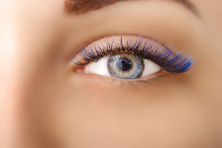 Eyelash Extension Procedure. Woman Eye with Long Blue Eyelashes. Ombre effect. Close up, selective focus.の写真素材