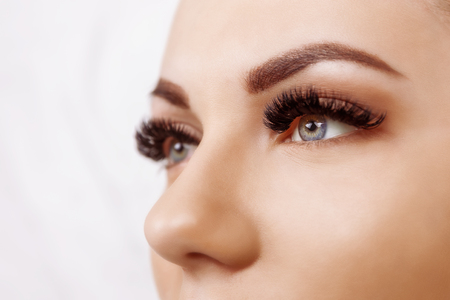 Eyelash Extension Procedure. Woman Eye with Long Eyelashes. Close up, selective focus. Hollywood, russian volumeの写真素材