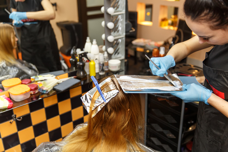 Professional hairdresser dyeing hair of her client in salon. Selective focus.の写真素材
