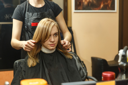 Professional hairdresser dyeing hair of her client in salon. Haircutter dry hair with hairdrier. Selective focus.の写真素材
