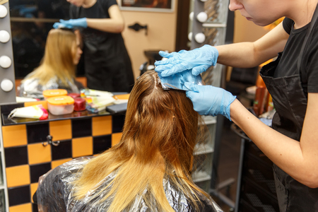 Professional hairdresser dyeing hair of her client in salon. Selective focus.の写真素材