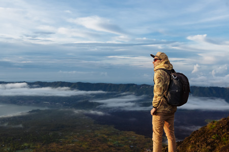 Man tourist looks at the sunrise on the volcano Batur on the island of Blai in Indonesia. Hiker man...