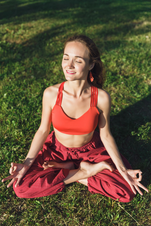 Young woman practicing yoga outdoors. Female meditate outdoor in the summer city park.の写真素材