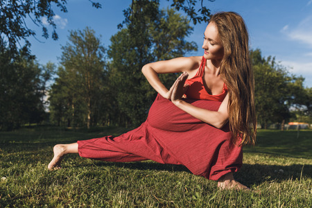Young woman doing yoga exercises in the summer city park. Health lifestyle concept.の写真素材