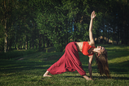 Young woman doing yoga exercises in the summer city park. Health lifestyle concept.の写真素材