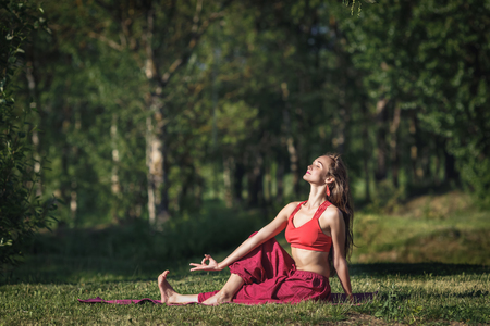 Young woman doing yoga exercises in the summer city park. Health lifestyle concept.の写真素材