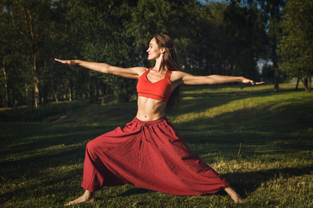 Young woman doing yoga exercises in the summer city park. Health lifestyle concept.の写真素材