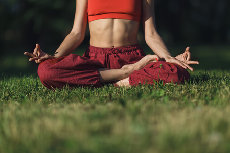 Young woman practicing yoga outdoors. Female meditate outdoor in the summer city park. Hands coseup, selective focus.の写真素材