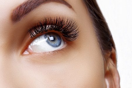 Eyelash Extension Procedure. Woman Eye with Long Blue Eyelashes. Ombre effect. Close up, selective focus.の写真素材