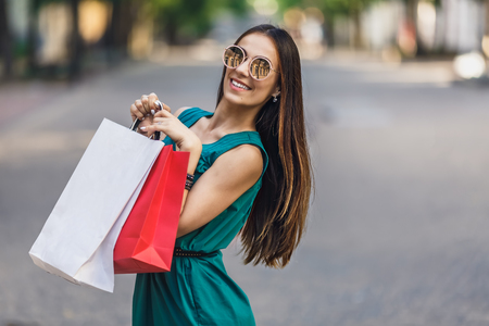 Portrait of young happy smiling woman with shopping bags enjoying in shopping. Positive emotions and Shopping day concept.の写真素材