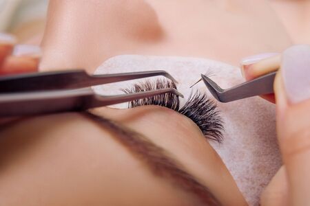 Eyelash Extension Procedure. Woman Eye with Long Blue Eyelashes. Close up, selective focus.の写真素材