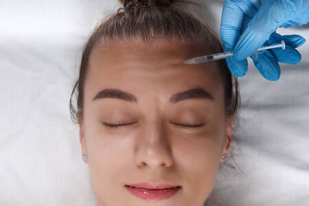 Closeup Portrait of young Caucasian woman getting cosmetic injection in forehead. People, cosmetology, plastic surgery and beauty concept.の写真素材