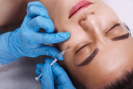 Facial Beauty Injections. Portrait Beautiful Young Woman Receiving Hyaluronic Acid Injection. Closeup Of Hands In Gloves Holding Syringe Near Attractive Female Face.の写真素材