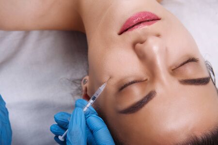 Facial Beauty Injections. Portrait Beautiful Young Woman Receiving Hyaluronic Acid Injection. Closeup Of Hands In Gloves Holding Syringe Near Attractive Female Face.の写真素材
