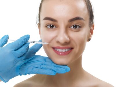 Facial Beauty Injections. Portrait Beautiful Young Woman Receiving Hyaluronic Acid Injection. Closeup Of Hands In Gloves Holding Syringe Near Attractive smiling Female Face.の写真素材