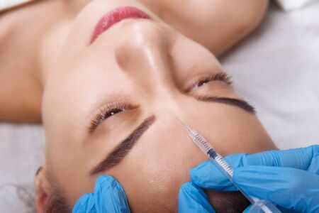 Closeup Portrait of young Caucasian woman getting cosmetic injection in forehead. People, cosmetology, plastic surgery and beauty concept.の写真素材