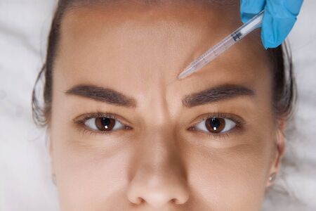 Closeup Portrait of young Caucasian woman getting cosmetic injection in forehead. People, cosmetology, plastic surgery and beauty concept.の写真素材