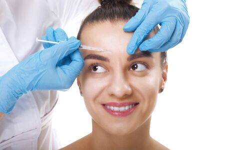 Closeup Portrait of young Caucasian woman getting cosmetic injection in forehead. People, cosmetology, plastic surgery and beauty concept.の写真素材