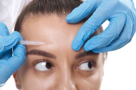 Closeup Portrait of young Caucasian woman getting cosmetic injection in forehead. People, cosmetology, plastic surgery and beauty concept.の写真素材