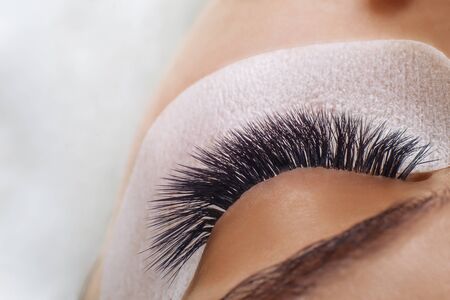 Eyelash Extension Procedure. Woman Eye with Long Blue Eyelashes. Ombre effect. Close up, selective focus.の写真素材