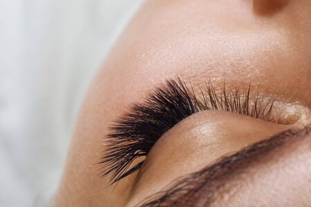 Eyelash Extension Procedure. Woman Eye with Long Blue Eyelashes. Ombre effect. Close up, selective focus.